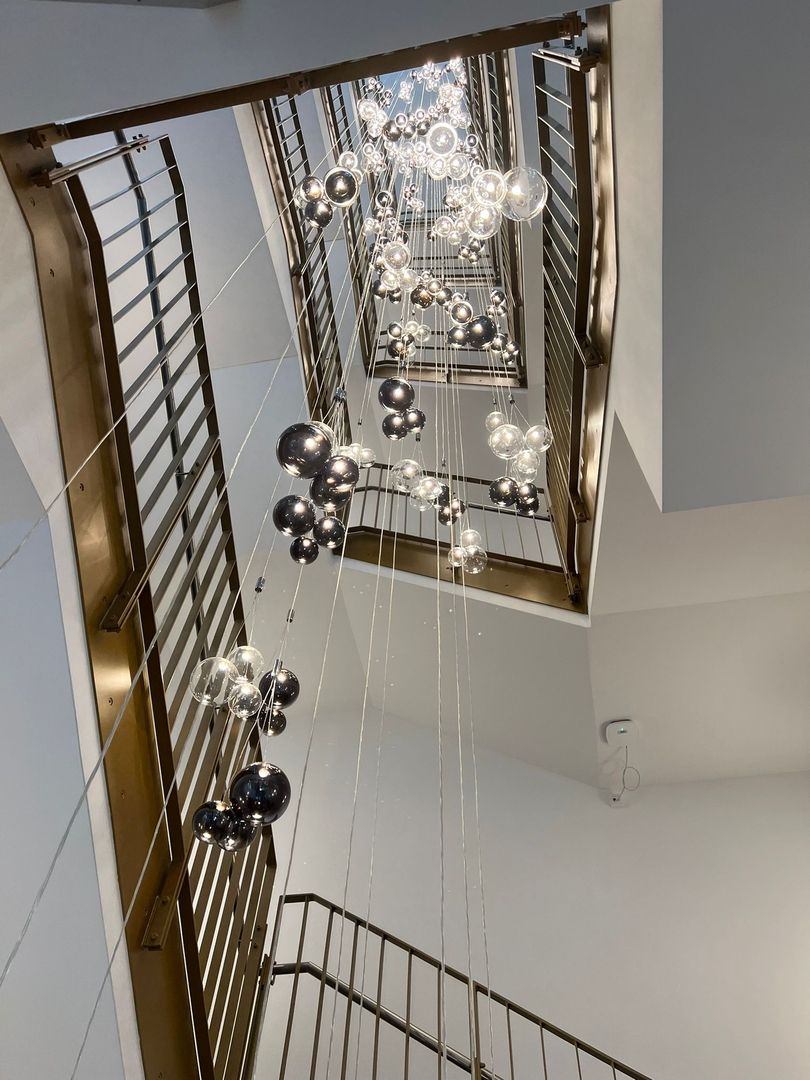 Eine Treppe mit einem Kronleuchter, der von der Decke hängt, beleuchtet den Raum elegant.