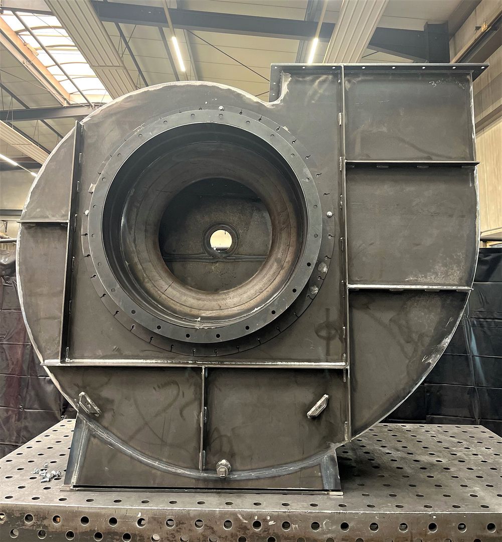Ein großer Industrieventilator steht auf einem Metalltisch.